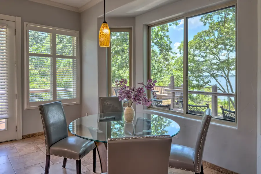 Round glass dining table for four in a window bay with lake views