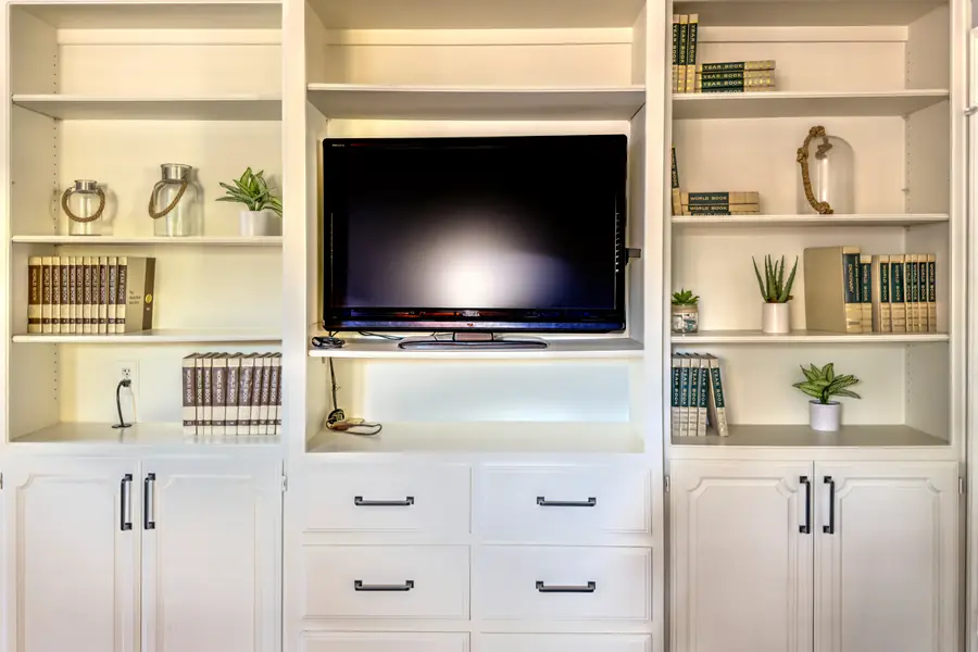 White built-in shelving with a TV, books and plants