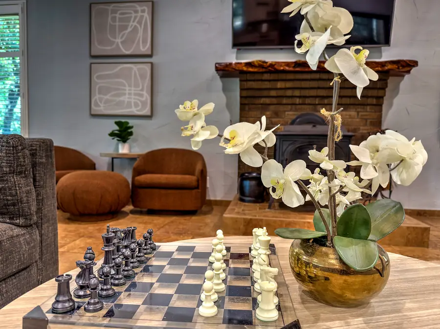 Chess set and orchids on the coffee table, wood stove behind