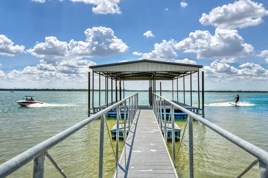 Walkway out to the covered boat dock, with a boat and a water-skier passing on the lake
