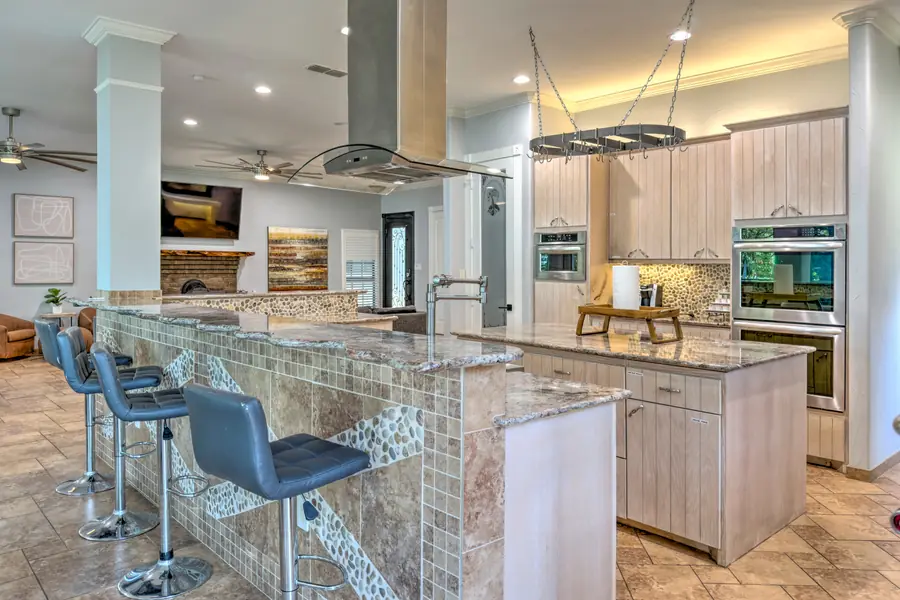Kitchen with bar seating, range hood and hanging pot rack