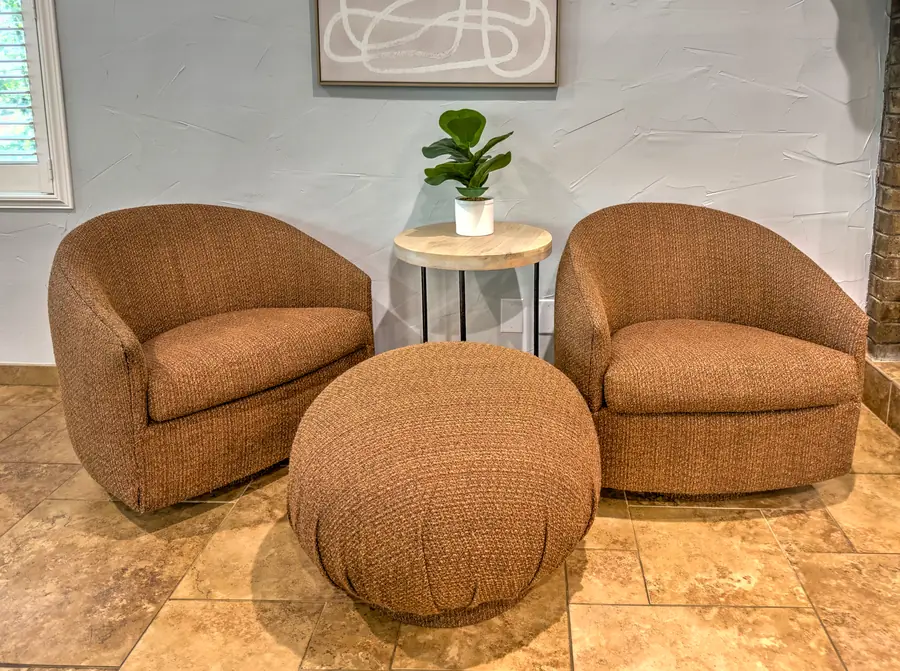 Two round swivel chairs and an ottoman in a corner nook
