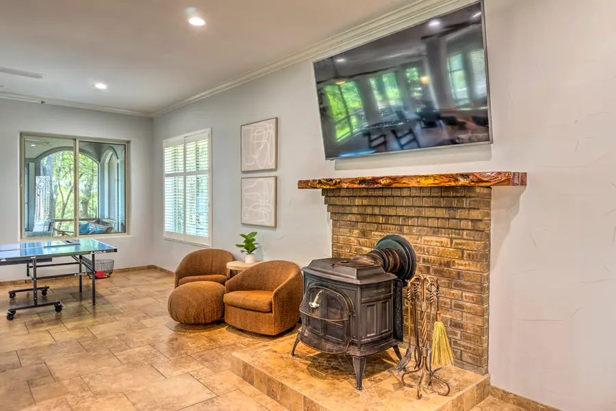 Cast-iron wood stove on a brick hearth beneath a wall-mounted TV
